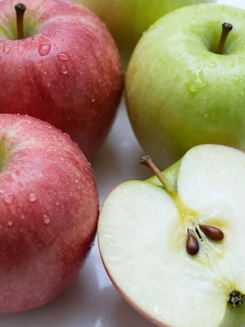 Mele fresche rosse e verdi su tagliere, a fette e intere, con succo