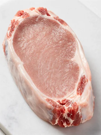 Pezzi di carne di vitello fresca chiara con spezie su tagliere di legno