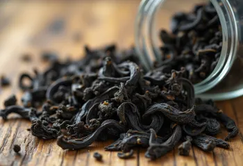 Foglie di tè nero sfuso in ciotola con cucchiaio di legno