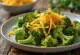 Cimette di broccoli verdi brillanti condite con pesto e formaggio fuso