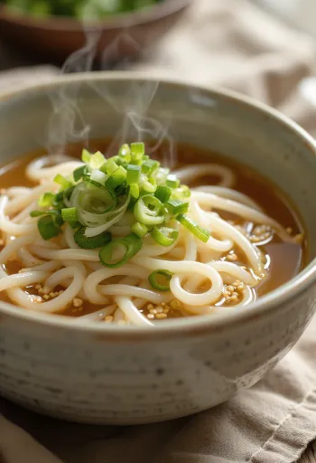 Kake udon servito in ciotola con brodo dashi, cipollotto fresco e semi di sesamo