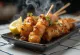 Kawa yakitori pelle di pollo su spiedino, servita con semi di sesamo e cipollotto fresco